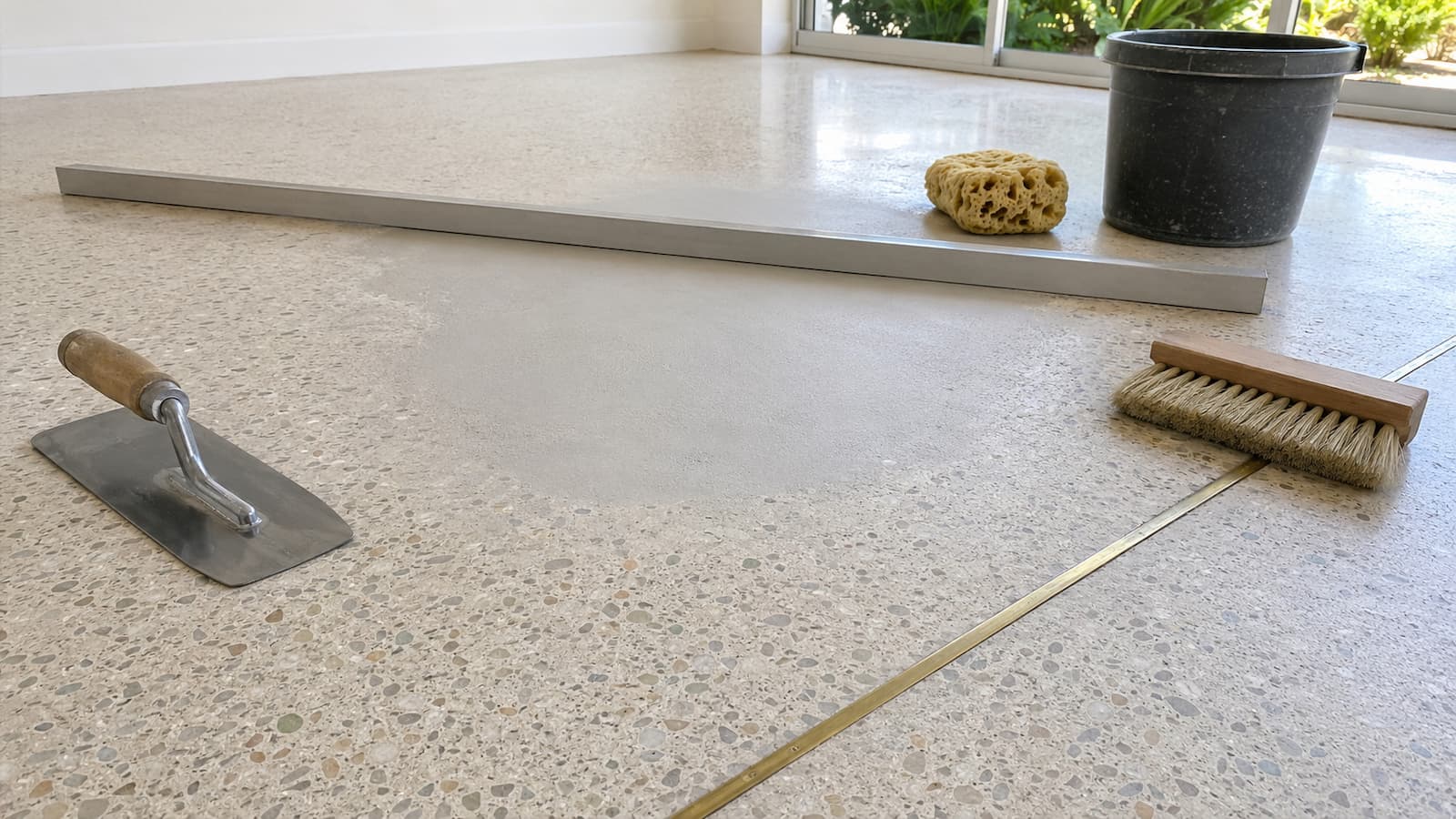 Feather-Finish Terrazzo Low Spot Repair Dry feather-finish patch correcting a shallow low spot in poured terrazzo before LVP