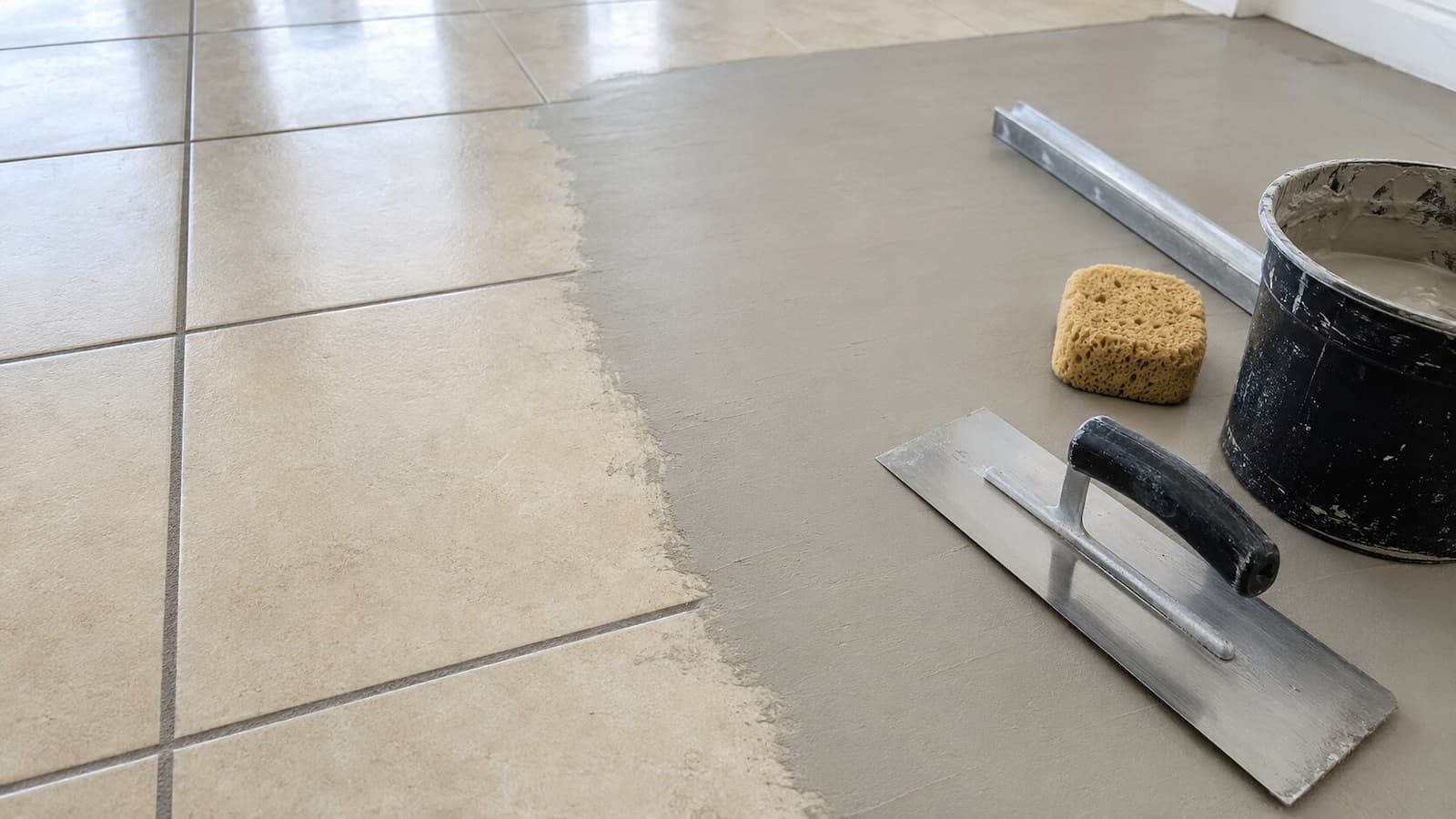Ceramic tile grout lines being covered with a thin feather-finish skim coat before LVP