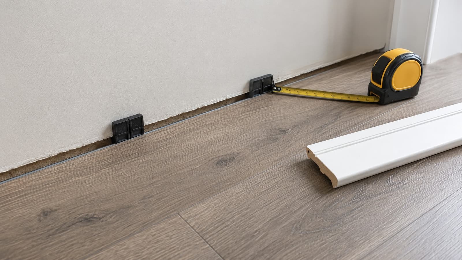 Perimeter expansion gap exposed behind removed baseboard at a floating LVP floor